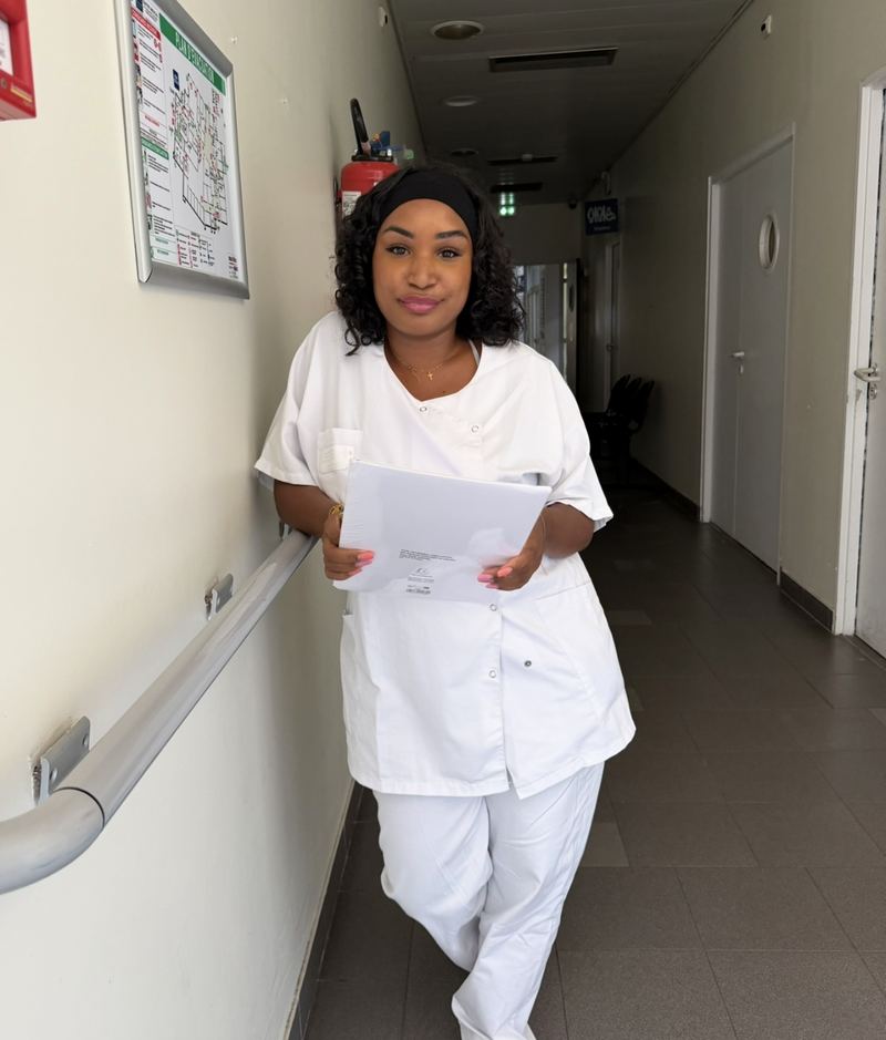 Mélissa Tatataa en tenue professionnelle dans un couloir d'établissement médico-social